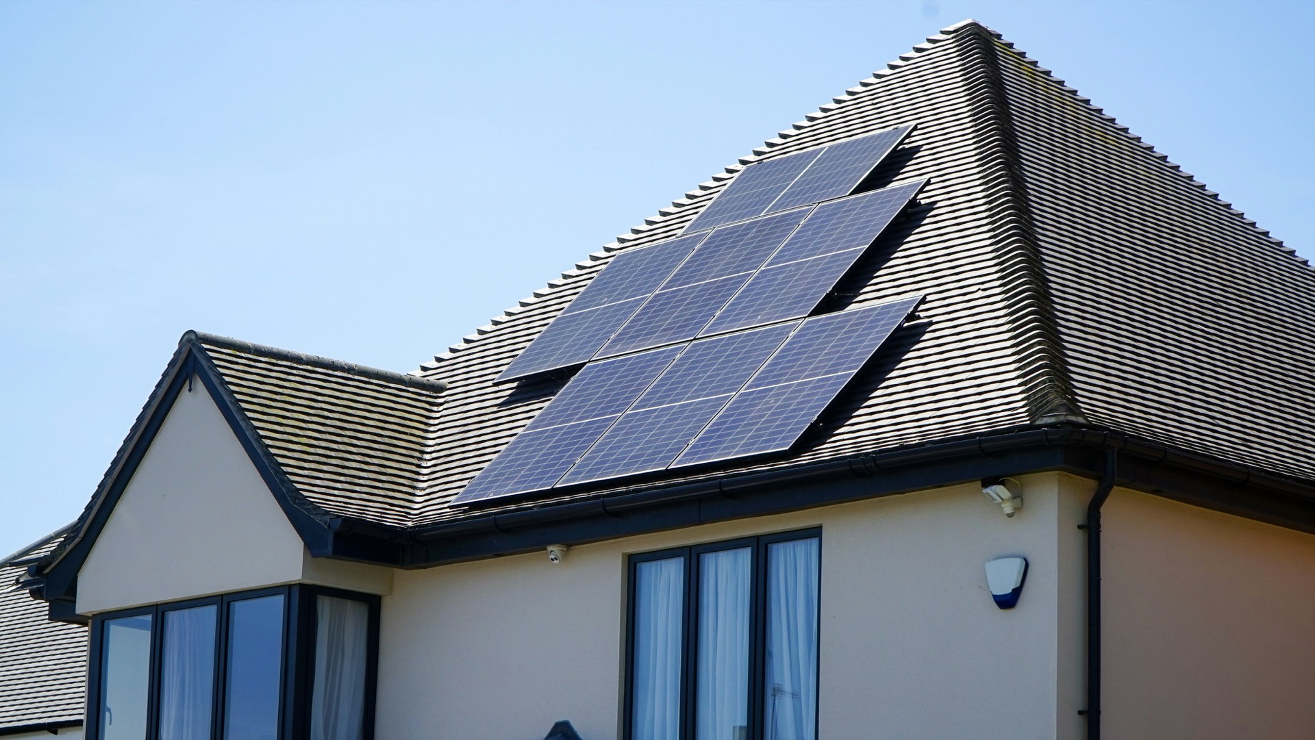 House with a tiled roof carrying a rooftop solar array on a clear day