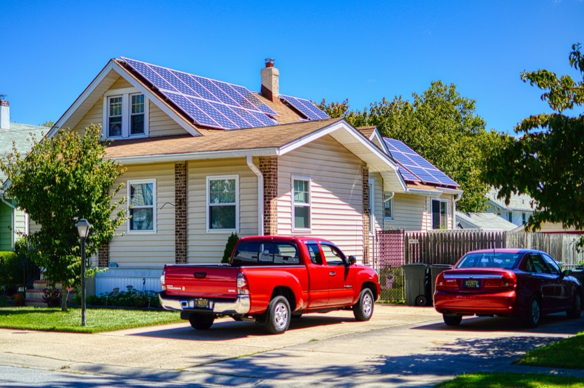Suburban house with rooftop solar panels and a pickup truck in the driveway